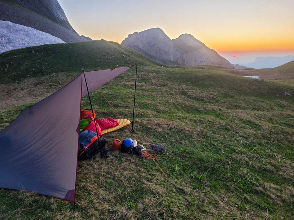coucher de soleil sur le bivouac qui a été atteint en parapente. Le tarp protège contre le vent qui descend de la montagne. Panorama de montagne de rêve pour ce vol bivouac en parapente