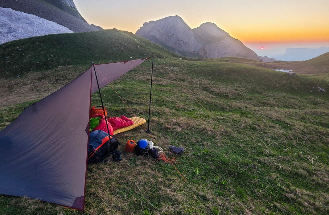coucher de soleil sur le bivouac qui a été atteint en parapente. Le tarp protège contre le vent qui descend de la montagne. Panorama de montagne de rêve pour ce vol bivouac en parapente